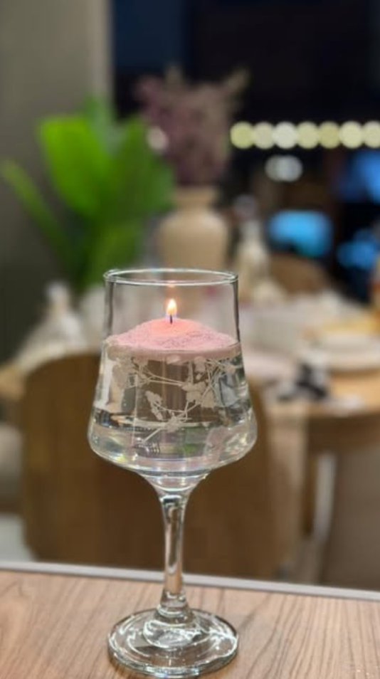Vela flotante rosada en una copa de cristal